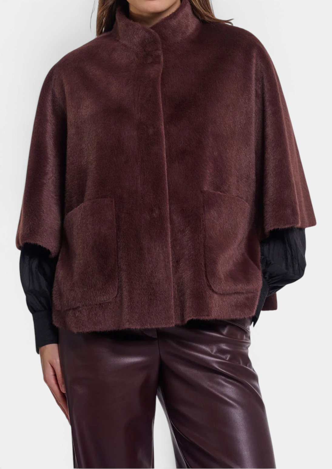 The Copper Shed Dewi cape in dark brown faux fur with front patch pockets and button closure over a black top.