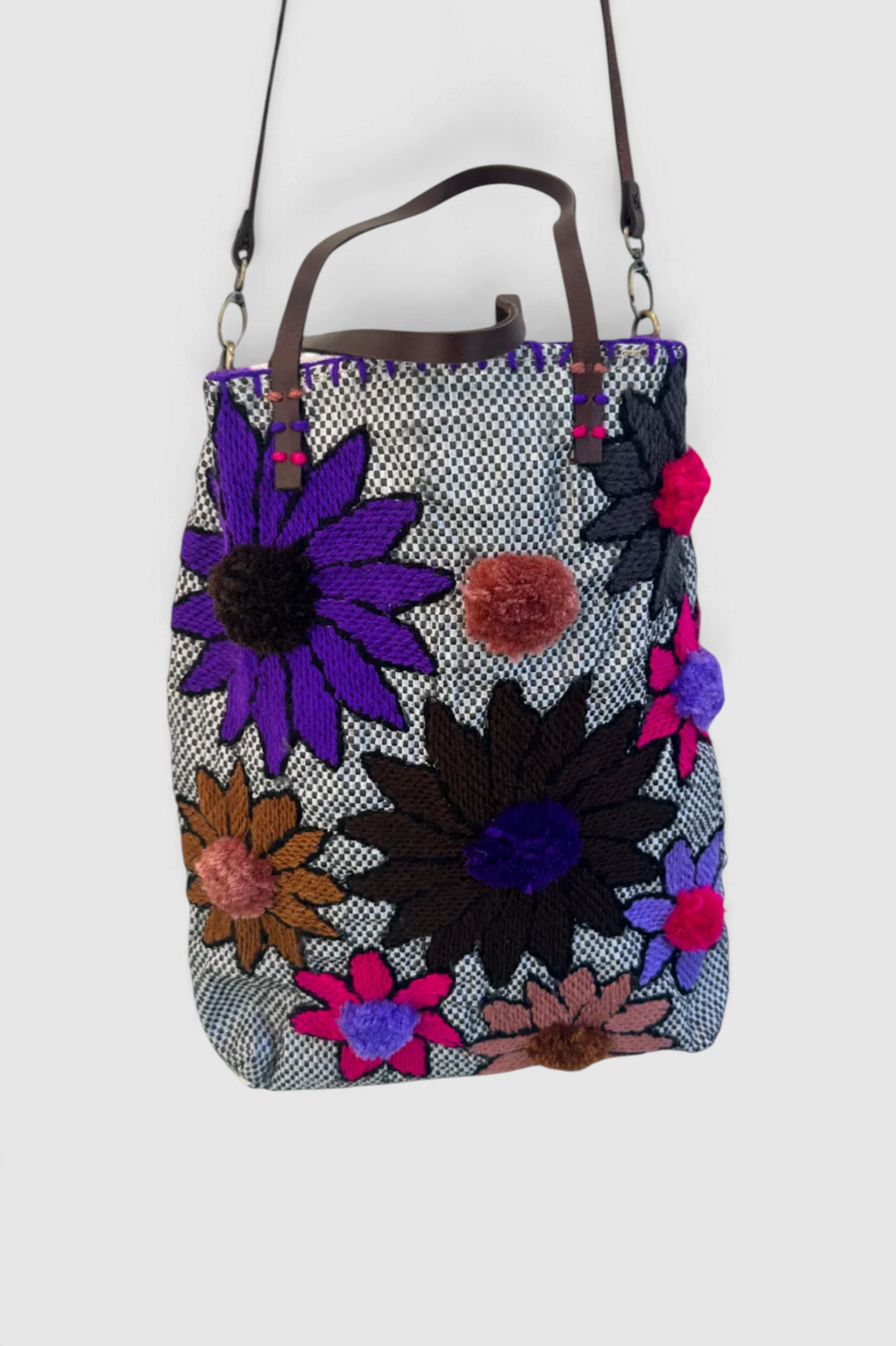 The Copper Shed En Shallah tote bag featuring a black and white woven pattern with vibrant floral pom-pom appliqués.