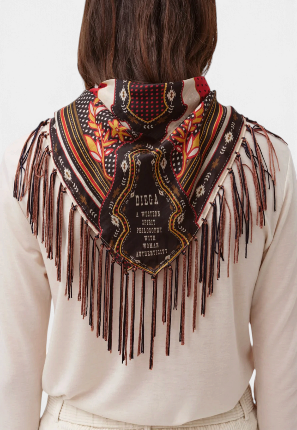 The Copper Shed Fareo silk scarf in chocolate and red with artisanal patterns and long fringe worn over a light top.