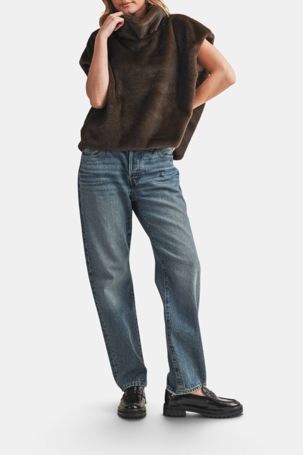The Copper Shed dark brown faux fur cap sleeve turtleneck top with a relaxed fit worn with blue jeans and loafers.