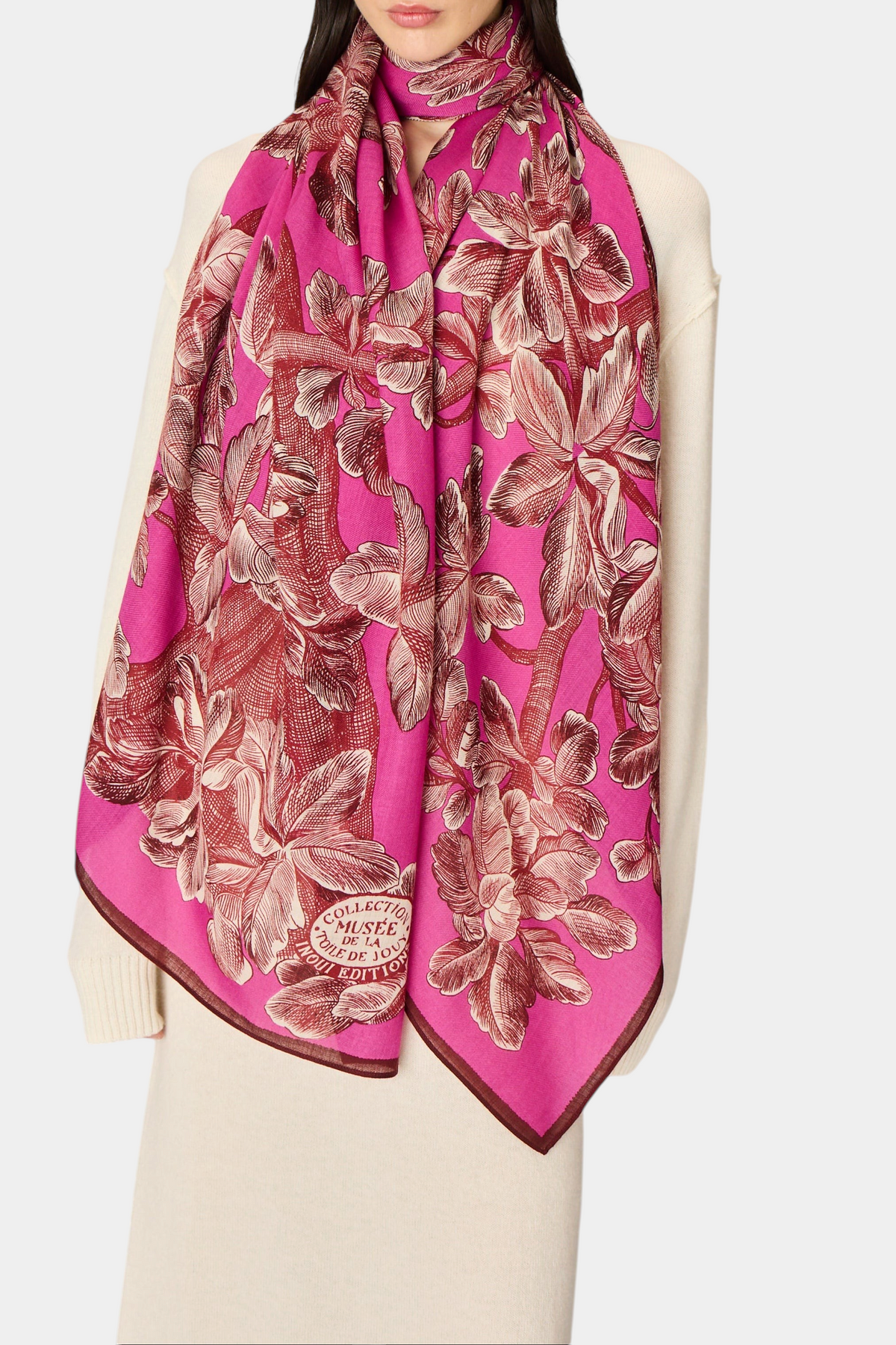 The Copper Shed Arboris fuchsia wool scarf with a detailed floral toile de jouy print worn over a cream sweater.