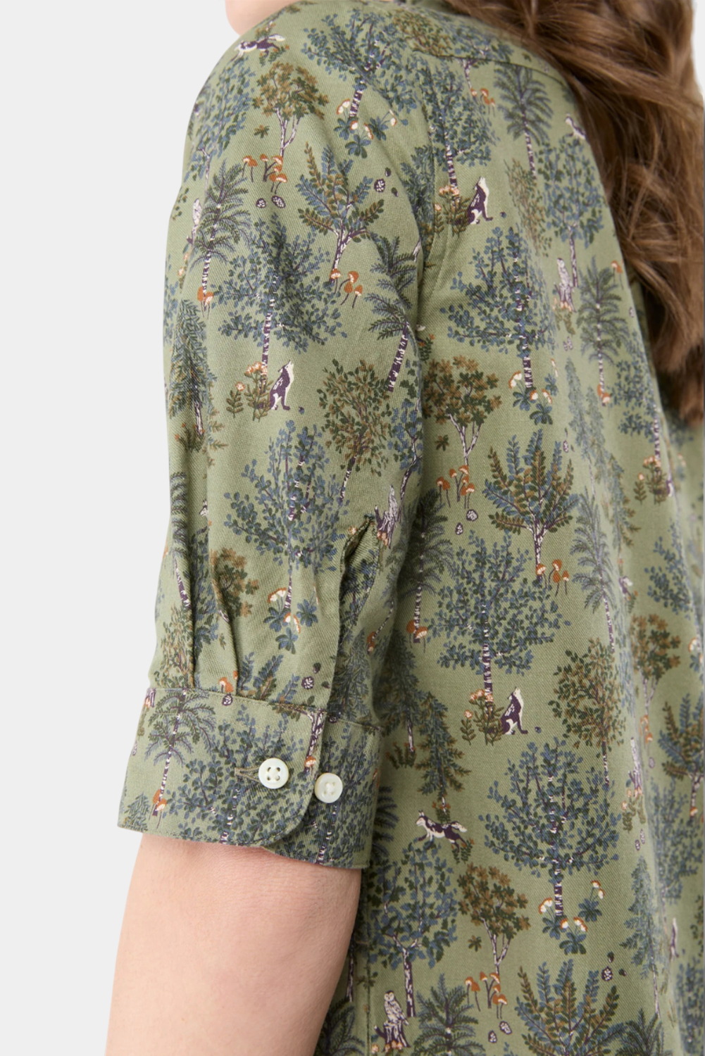 The Copper Shed elbow-sleeve frill dress in green Liberty cotton fabric with a whimsical forest print and button cuffs.