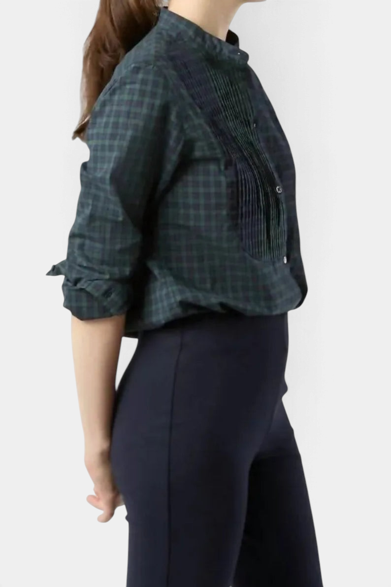 The Copper Shed Hattie shirt in Blackwatch tartan featuring a pleated bib-front, mandarin collar, and long sleeves.