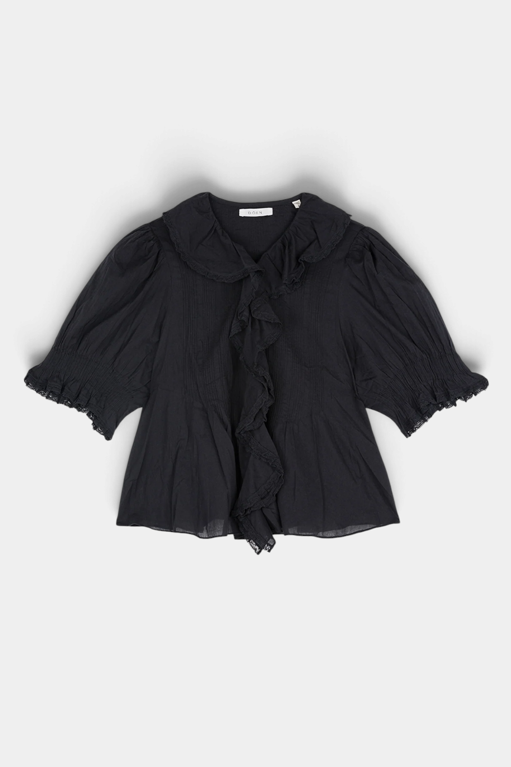 The Copper Shed Henri top in black organic cotton voile with lace-trimmed ruffles, pintucks, and puffed sleeves.