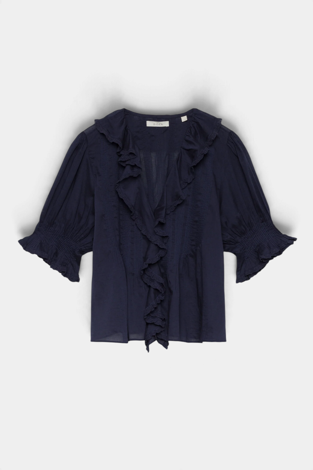The Copper Shed Henri top in navy organic cotton voile with a V-neck, lace-trimmed ruffles, and puffed sleeves.