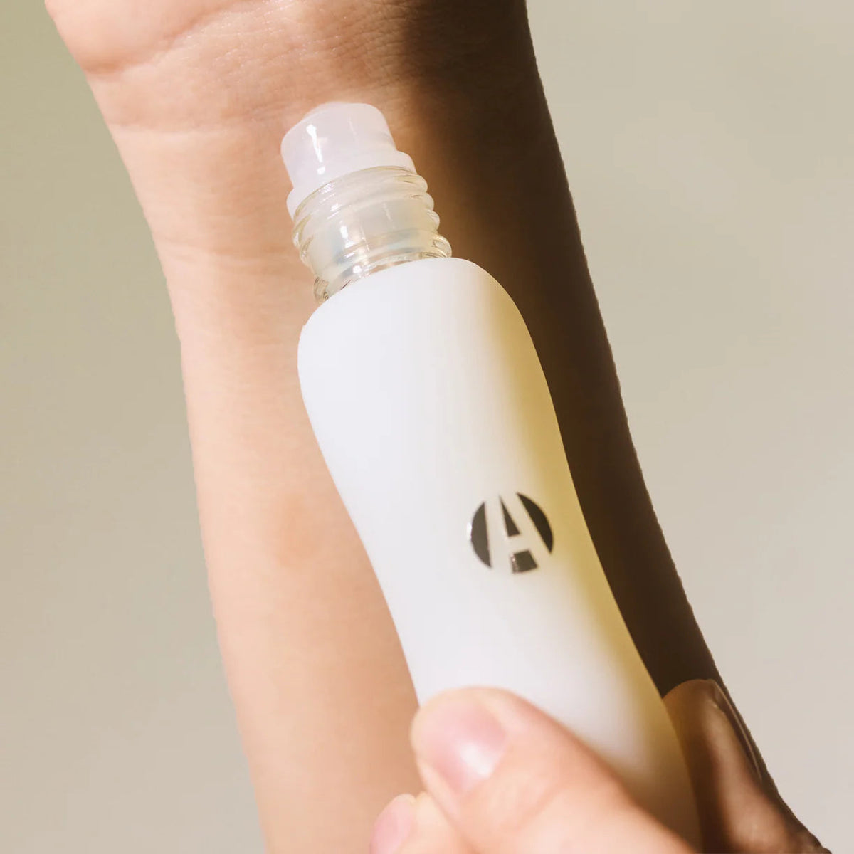 The Copper Shed IF perfume oil in a white frosted glass roll-on bottle being applied to a wrist.