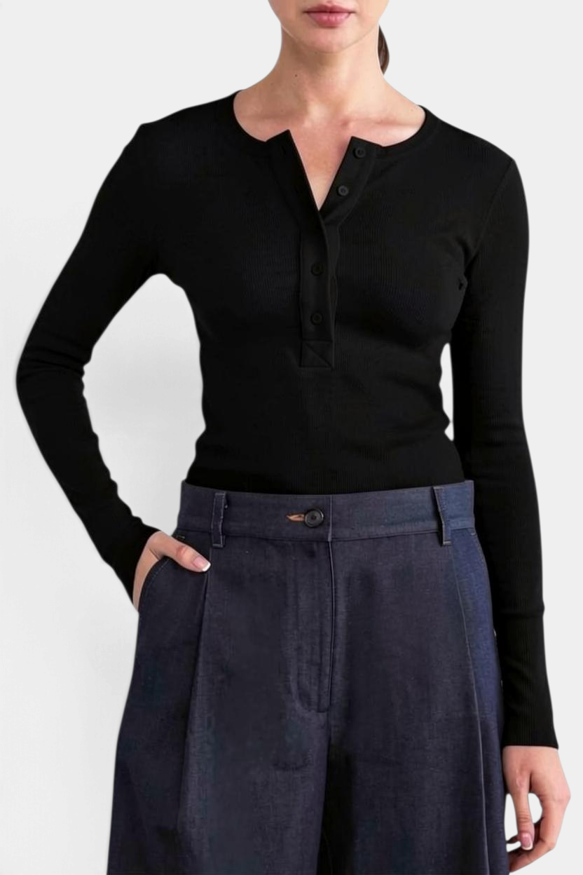 The Copper Shed Kaia long sleeve black ribbed henley tee with a five-button placket worn with dark denim trousers.