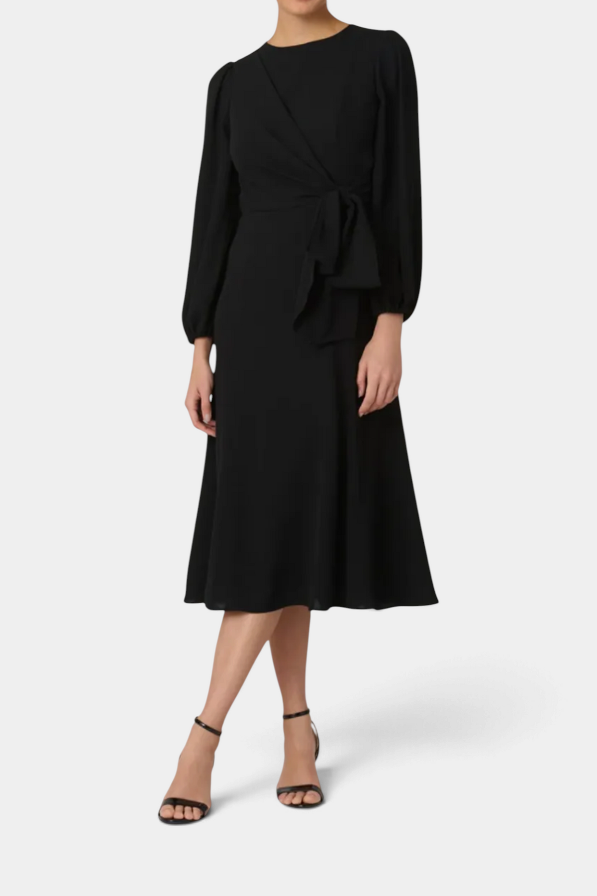 The Copper Shed Kathleen midi dress in black stretch crepe with a draped bodice, asymmetric waist bow, and long sleeves