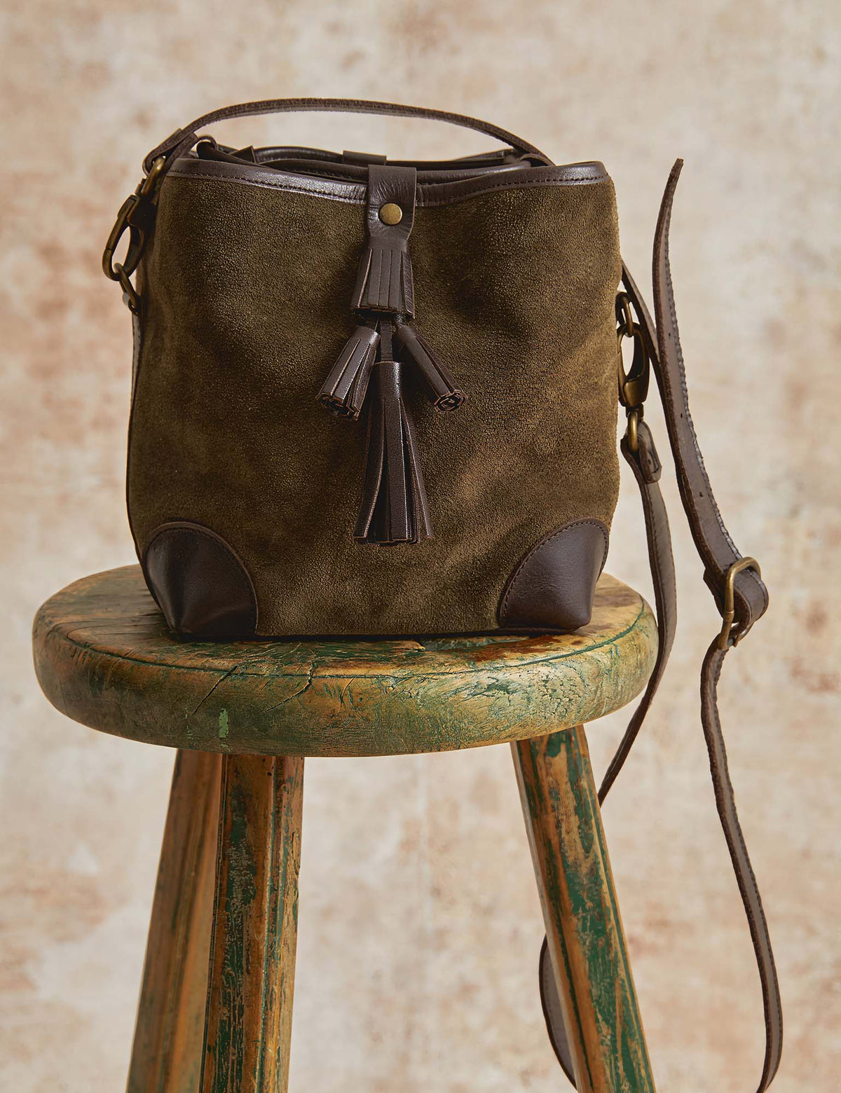 The Copper Shed khaki suede crossbody bag with bitter chocolate leather trim and a tiered tassel detail.