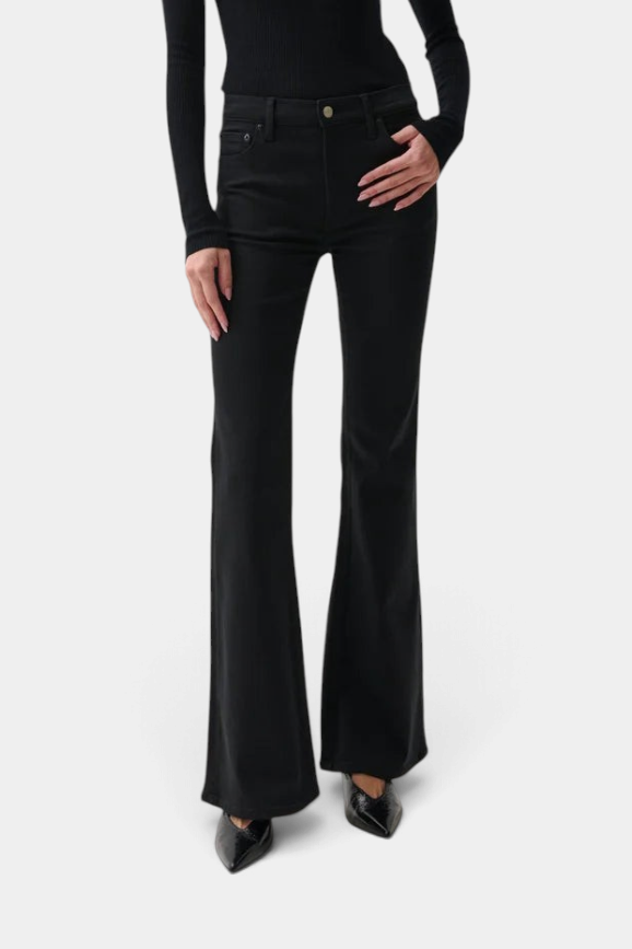 The Copper Shed Kinsley mid-rise ultra flare black stretch denim jeans on a model with a slim fit and wide leg.