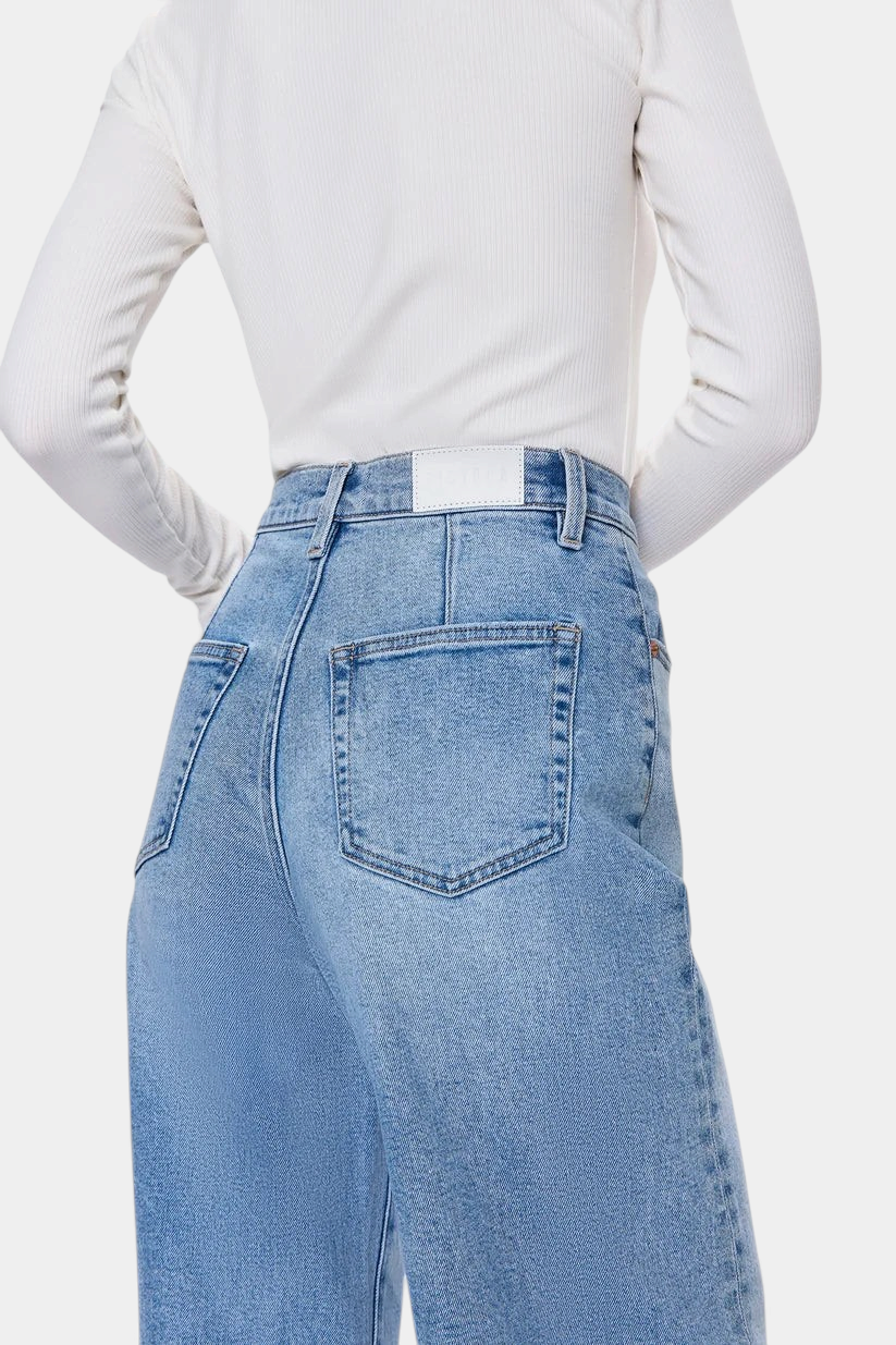 The Copper Shed Kyra high rise jeans in light vintage wash denim featuring back yoke seams and a white leather patch.