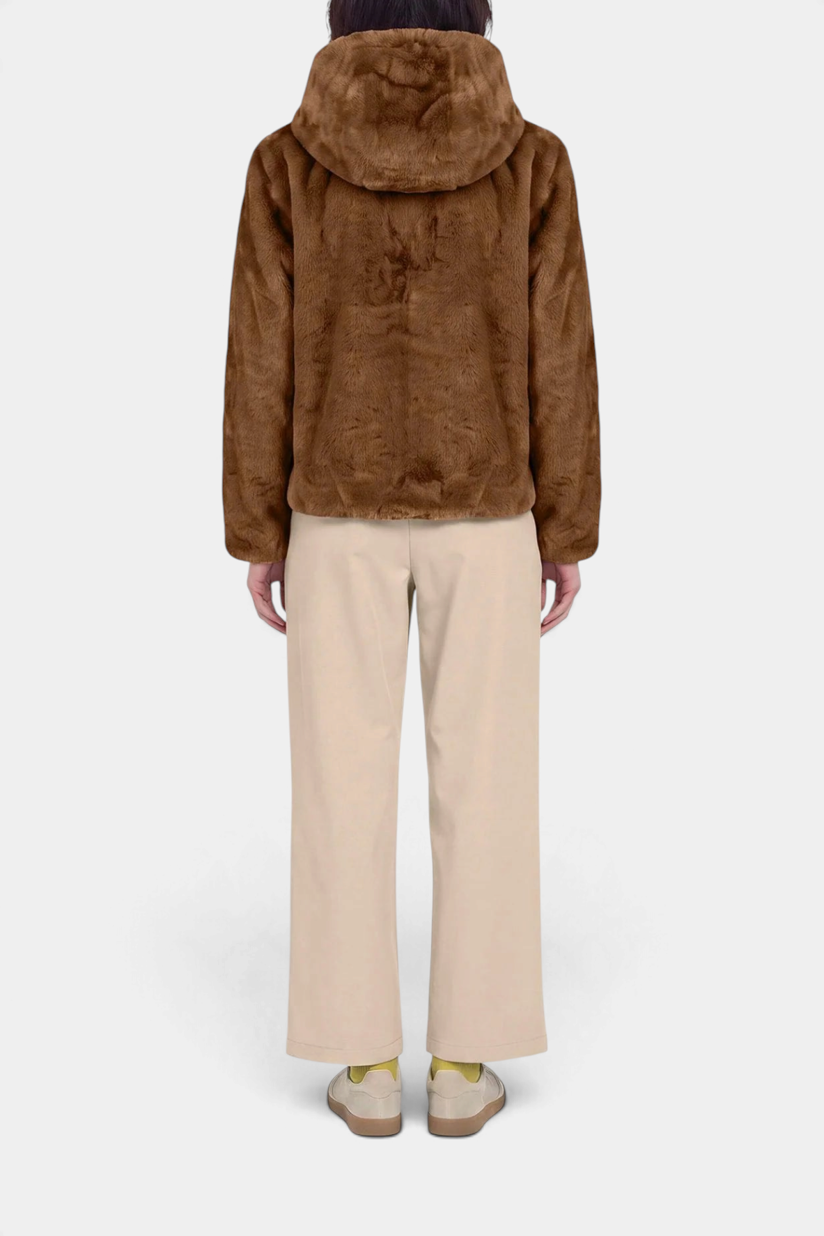 The Copper Shed Laila reversible hooded jacket in brown faux fur, shown from the back on a model with beige trousers.
