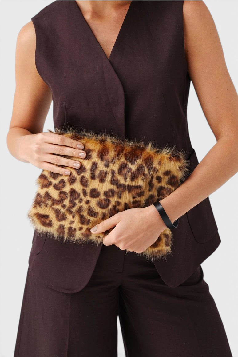 The Copper Shed leopard print faux fur clutch bag with a detachable leather wrist strap held by a model.