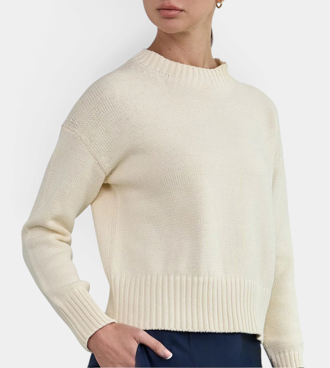 The Copper Shed Logan cotton crewneck sweater in cream with a relaxed fit, high-low hem, and wide ribbed cuffs.