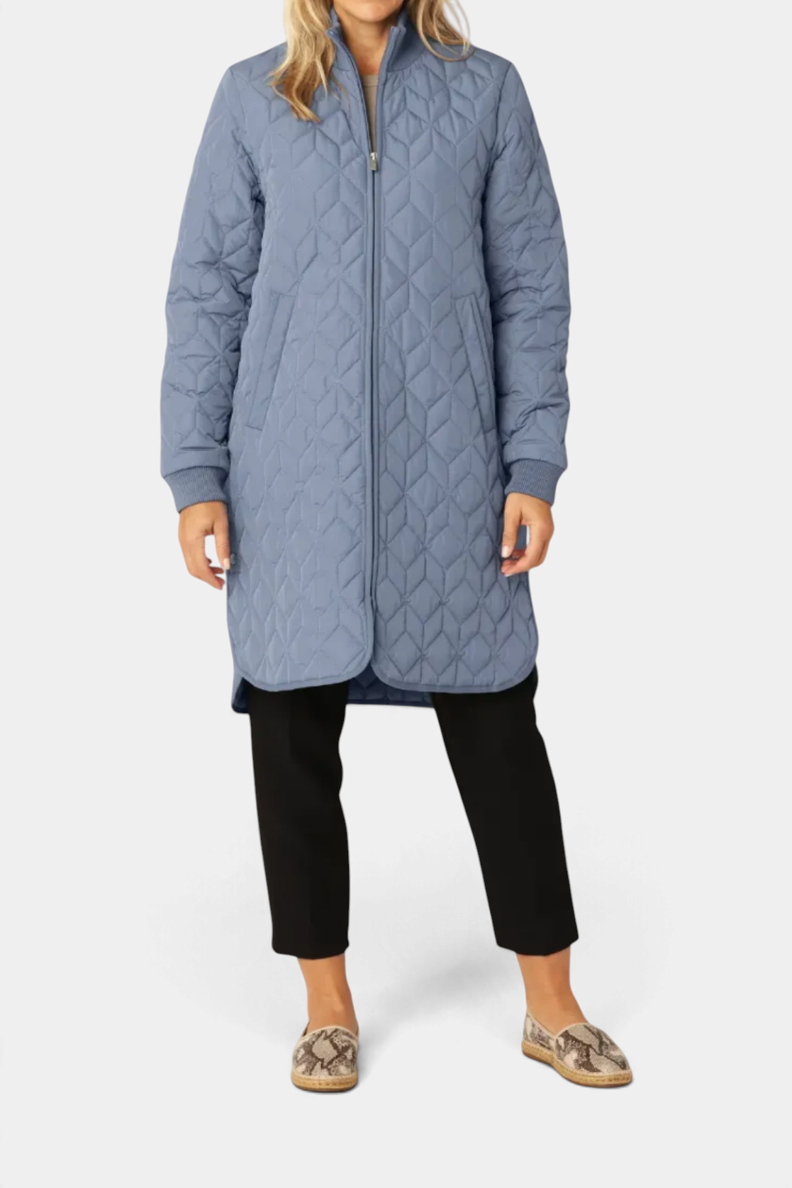 The Copper Shed long blue padded quilt jacket with a high ribbed neckline and 2-way zipper worn by a model