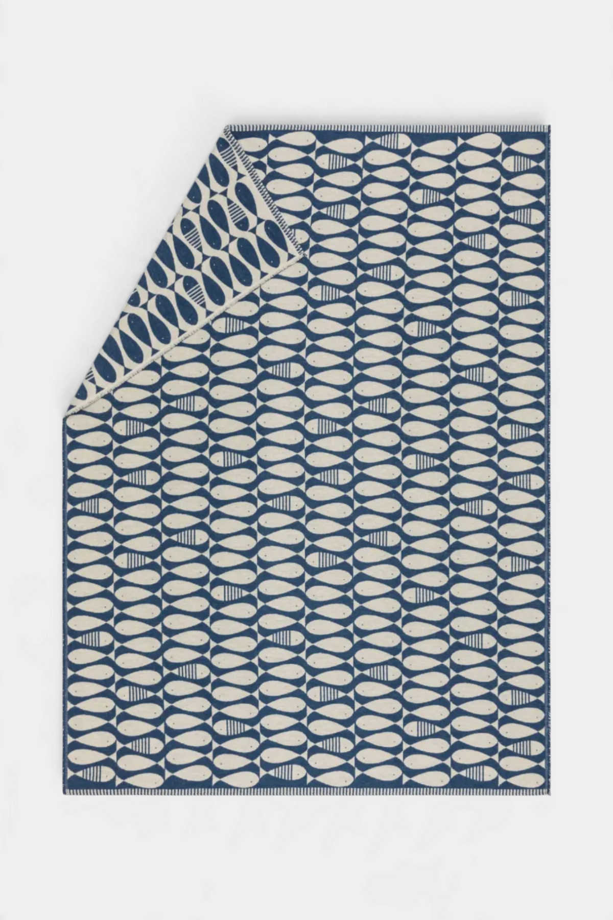 The Copper Shed LUCA recycled cotton throw in navy and cream with a playful sardine fish pattern and frayed edges.
