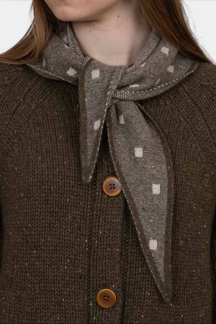 The Copper Shed Mia triangle cashmere neckerchief in brown with a subtle white geometric pattern worn around the neck.