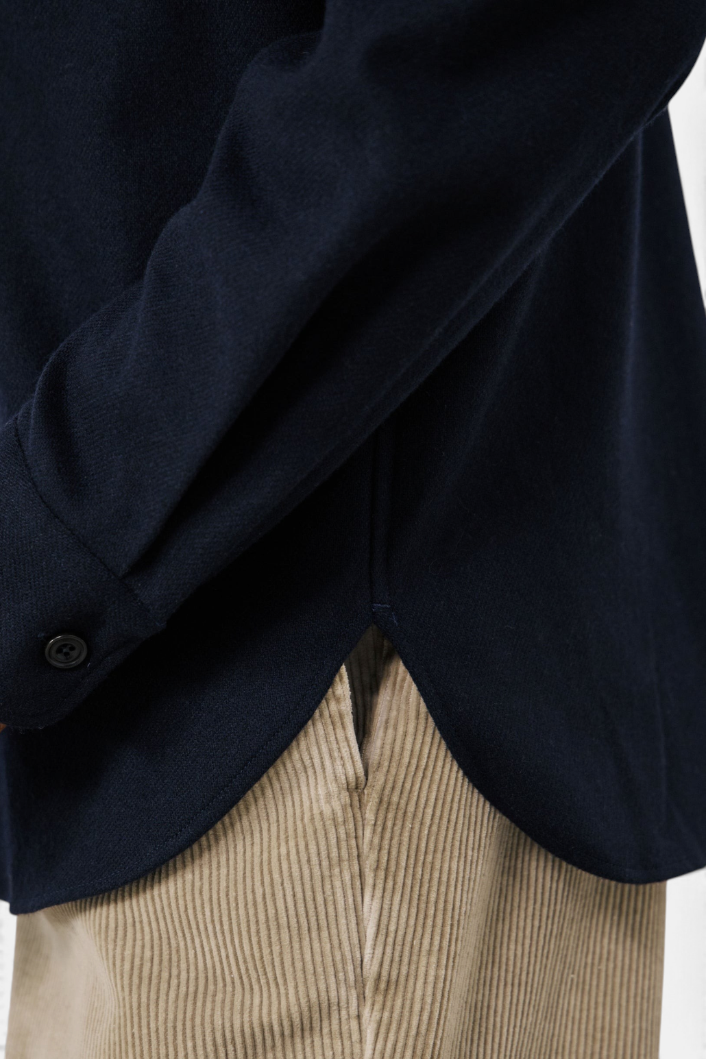 The Copper Shed navy blue boiled wool shirt featuring a curved hem and buttoned cuff detail.