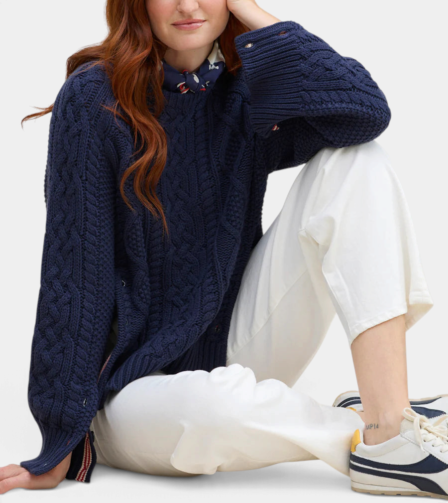 The Copper Shed navy blue cable knit pullover with striped side ribbon detail and buttoned cuffs worn by a model.