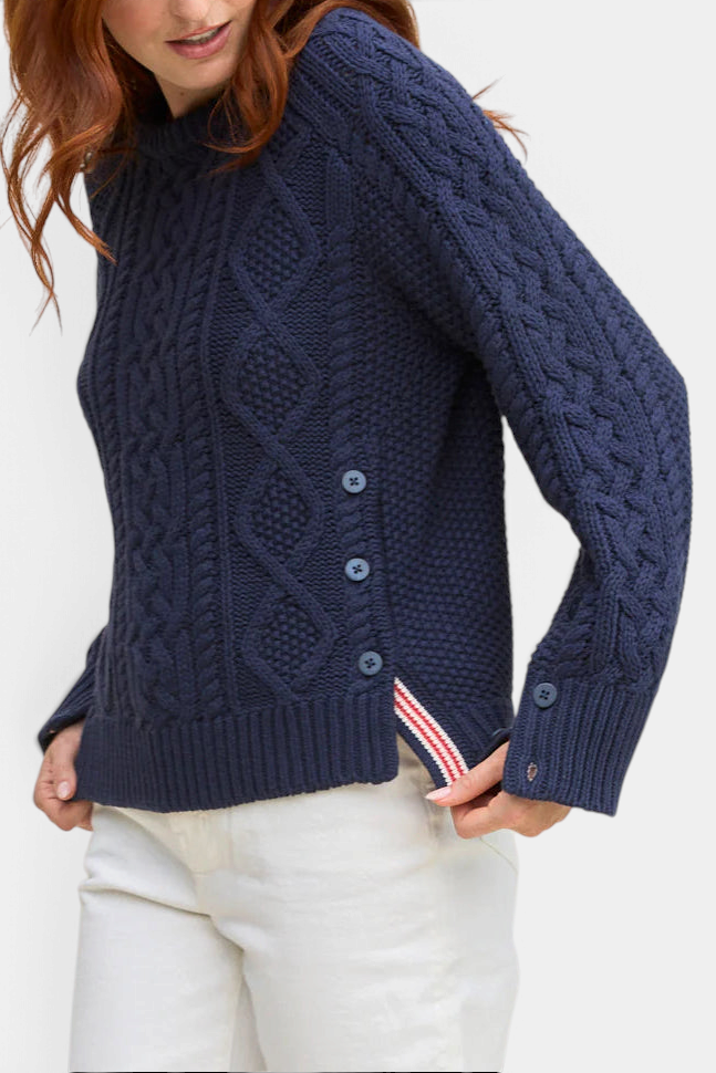 The Copper Shed navy blue cable knit pullover with side button vents and striped ribbon detail on a model