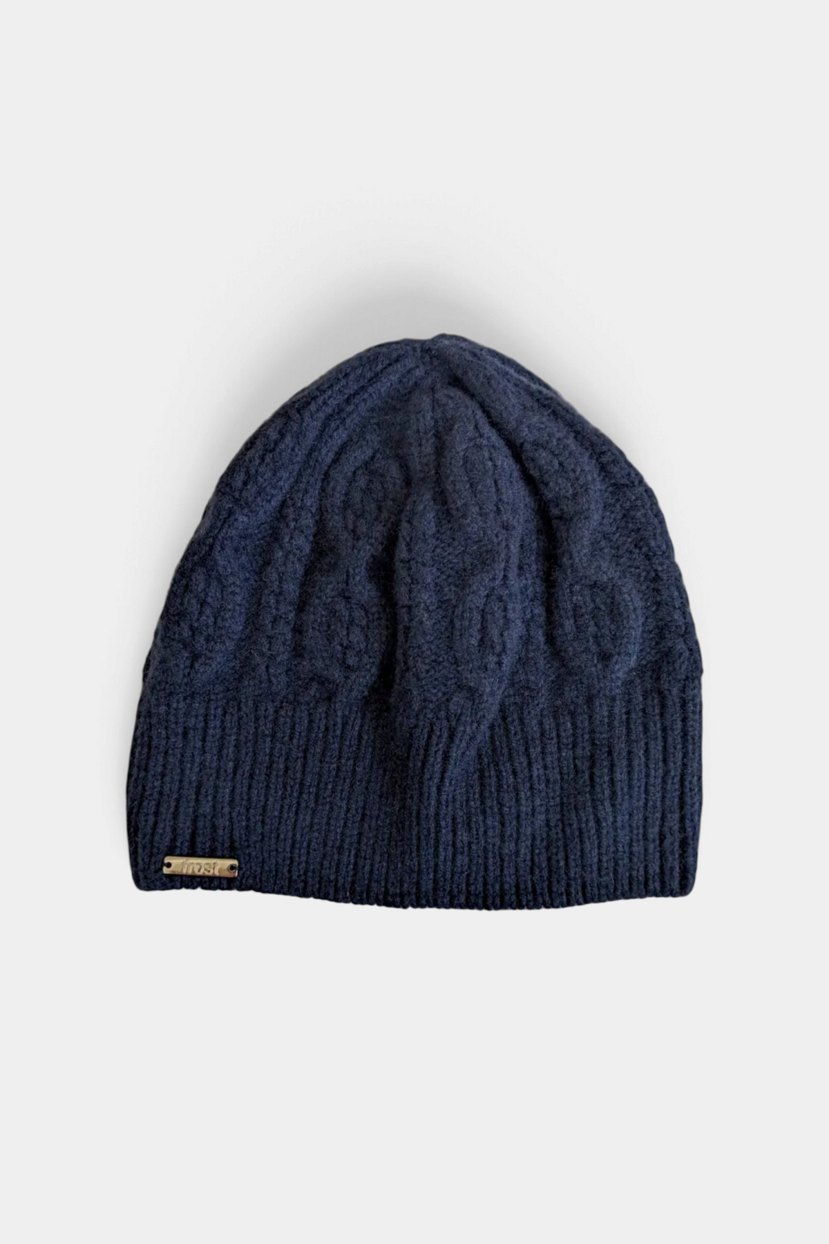 The Copper Shed navy blue cable knit beanie made from a soft cashmere and merino wool blend with a small metal tag.