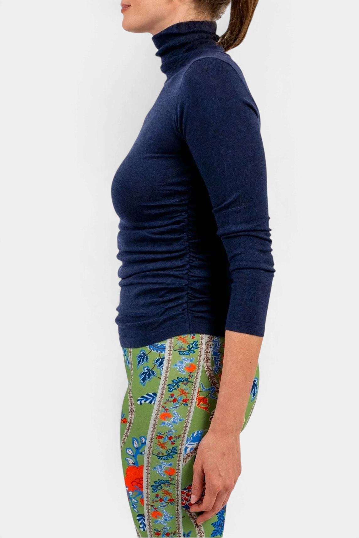 The Copper Shed navy blue cashmere turtleneck sweater with side ruching worn by a woman in profile view