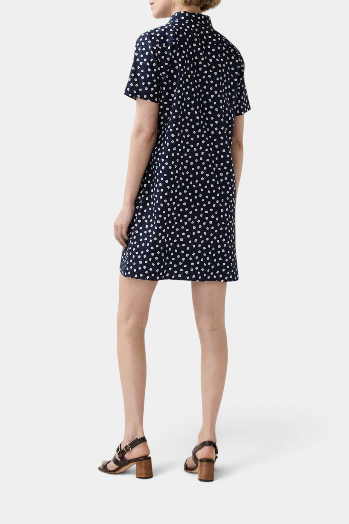 The Copper Shed short-sleeved navy blue crinkle cotton popover dress with a white daisy floral print, back view.
