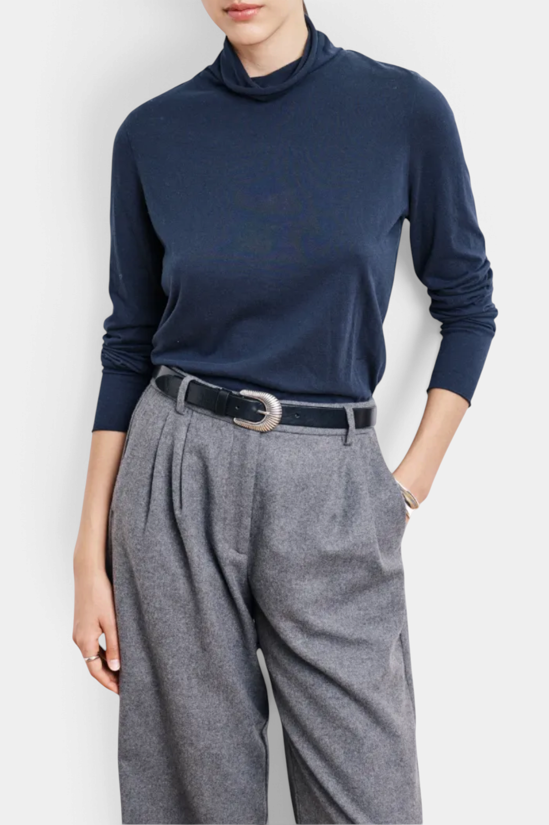 The Copper Shed navy blue long-sleeved knit T-shirt with a stand-up collar worn with grey trousers and a black belt.