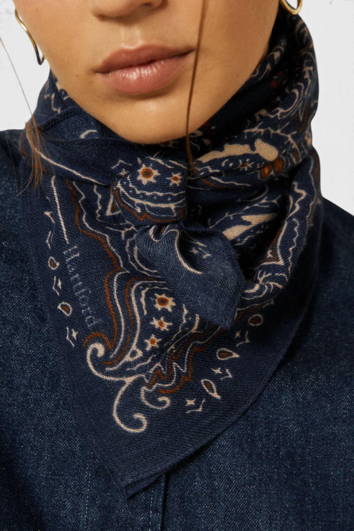 The Copper Shed navy blue wool bandana scarf with intricate paisley print tied around a woman's neck