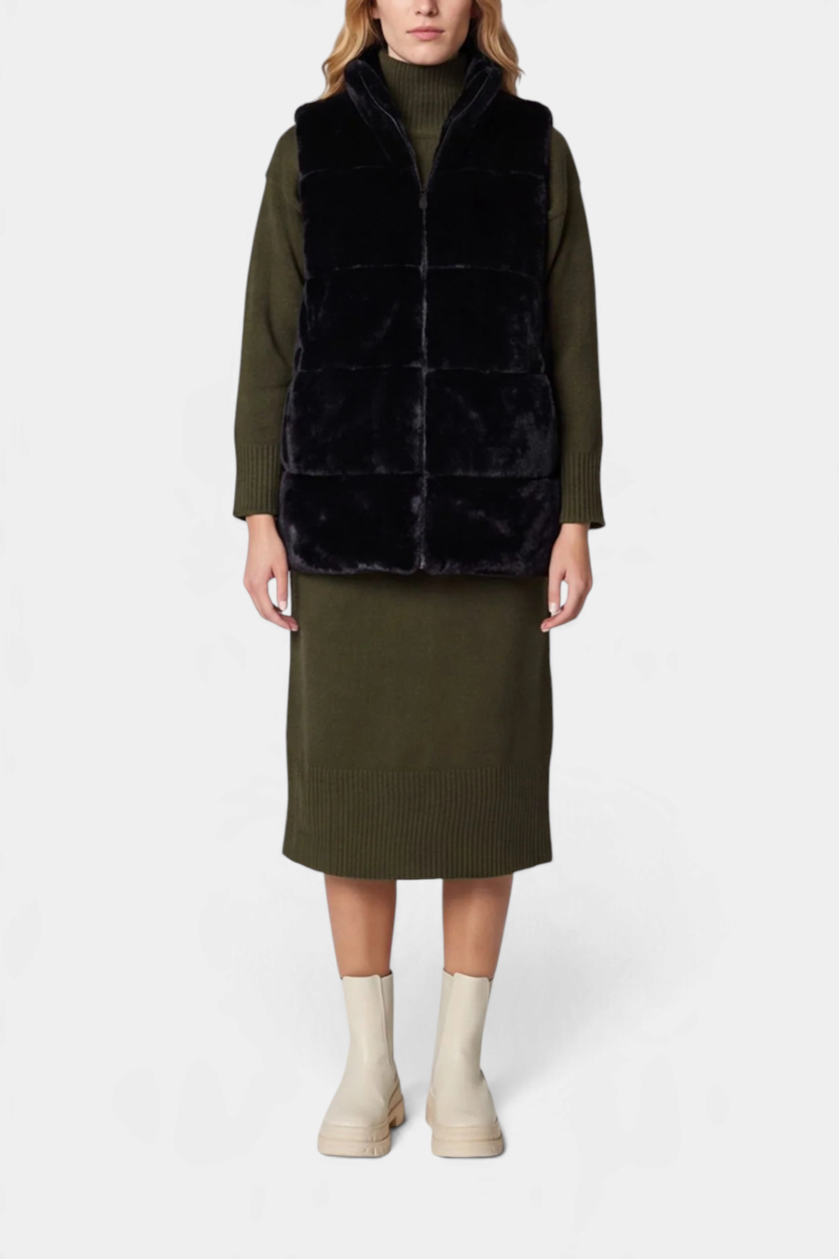 The Copper Shed Nives reversible black faux fur vest with a stand-up collar worn over an olive green sweater dress.