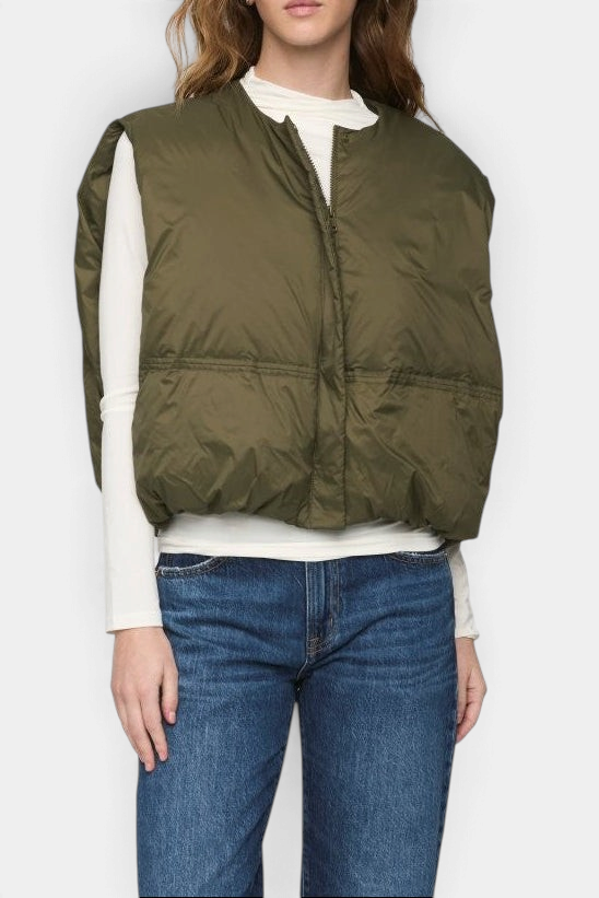 The Copper Shed Catarina olive green quilted nylon puffer vest worn over a white long-sleeve top and blue jeans.