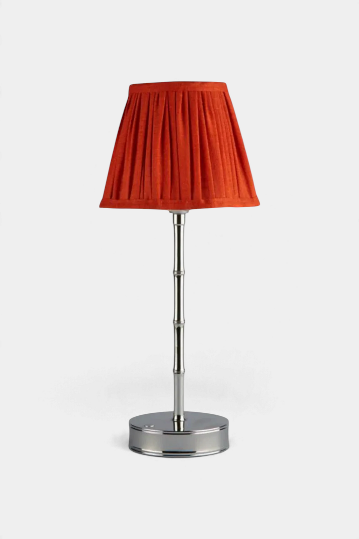 The Copper Shed orange pleated scalloped lampshade on a silver bamboo-style lamp base against a plain background.
