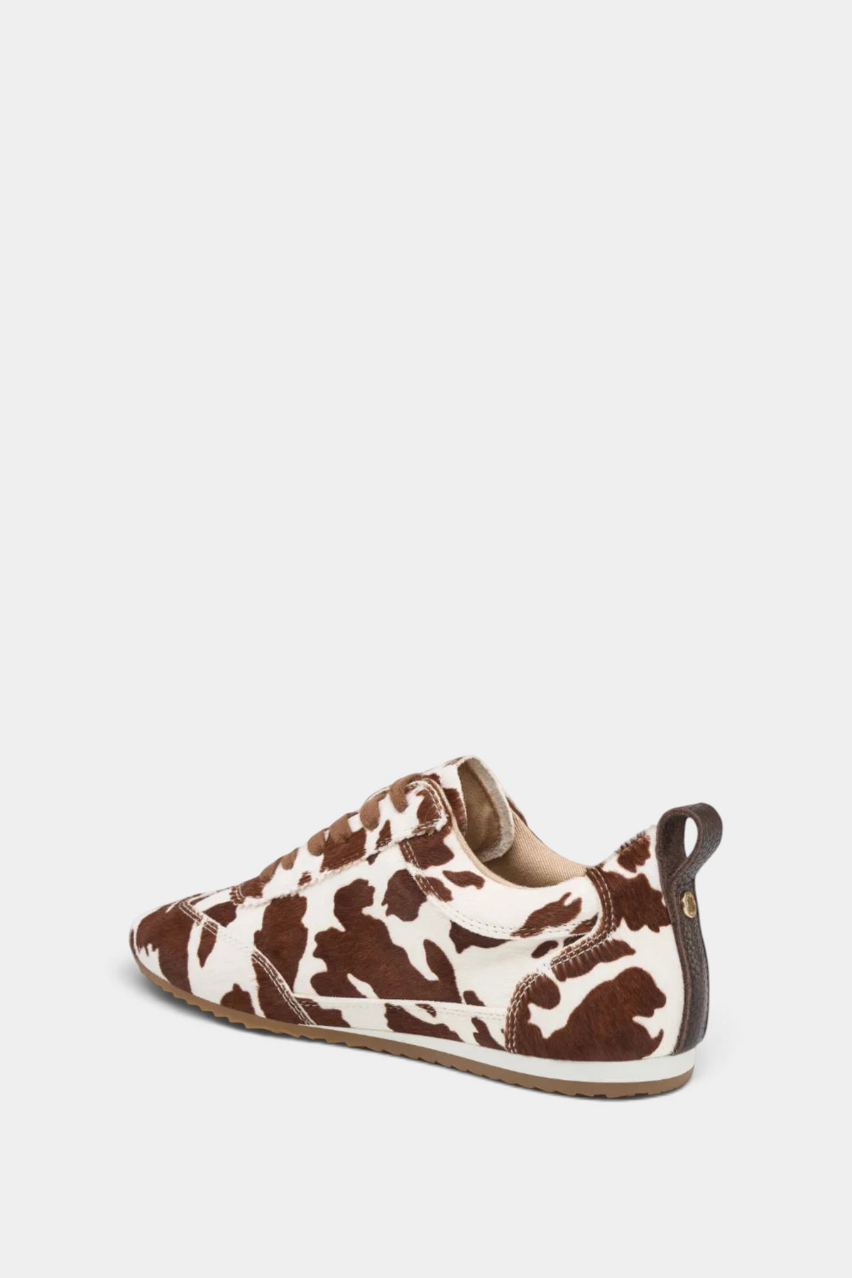 The Copper Shed Paige leather sneaker featuring a brown and white cow print pattern with a low-profile design.
