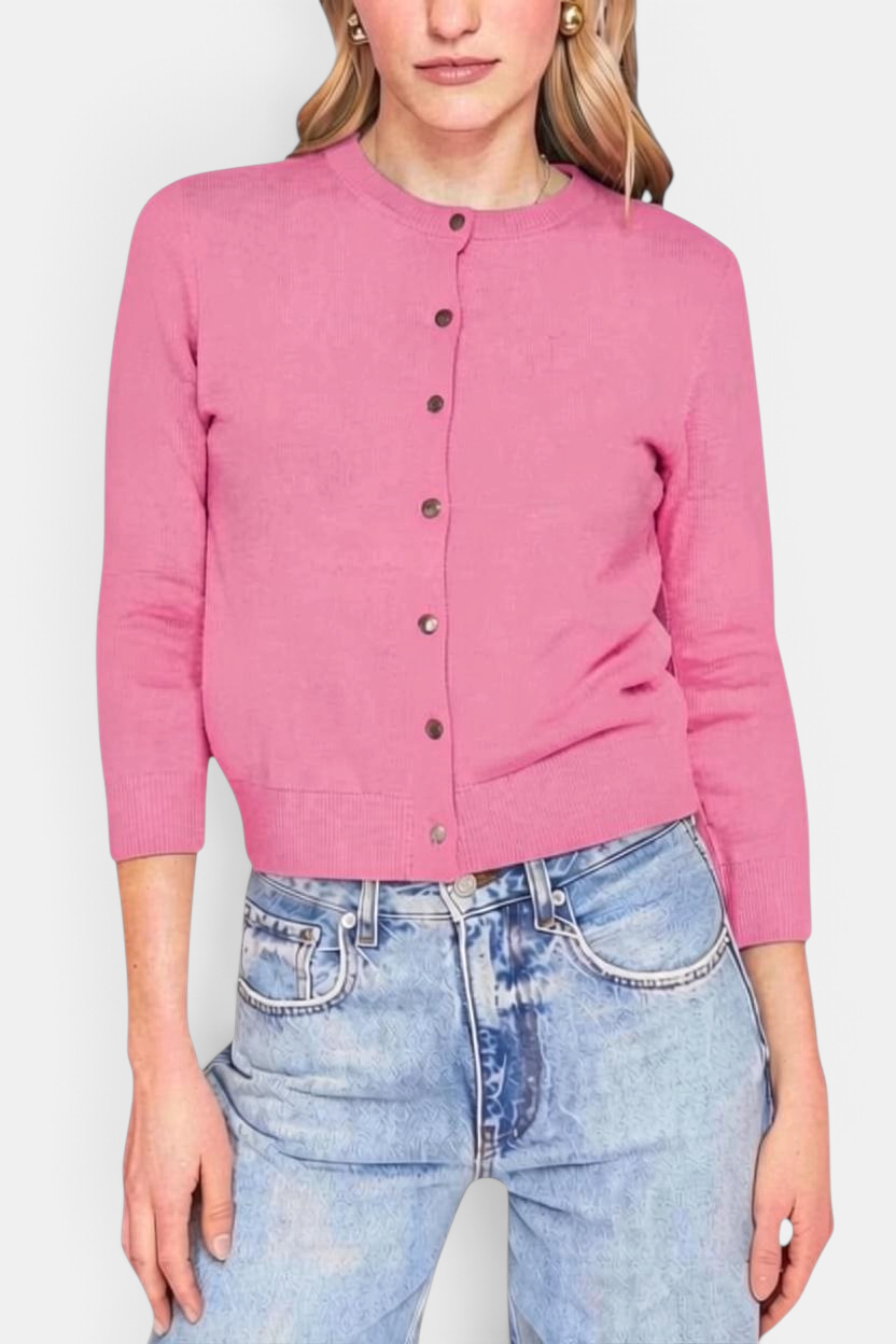 The Copper Shed pink cashmere baby cardigan with a crew neck, button front, and ribbed hem worn by a model.