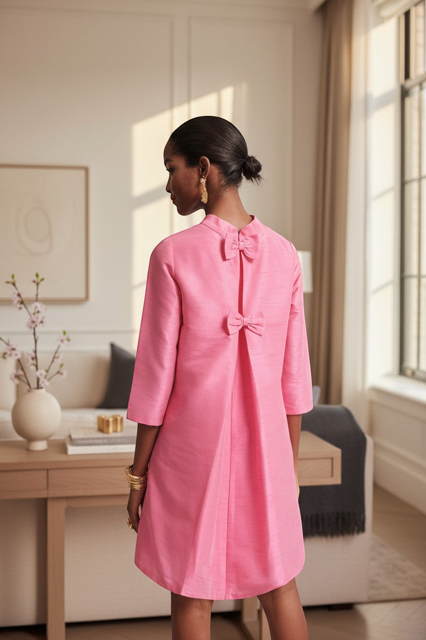 The Copper Shed pink silk mini dress with mock neckline and back bow details. 3/4 sleeves and A-line skirt.