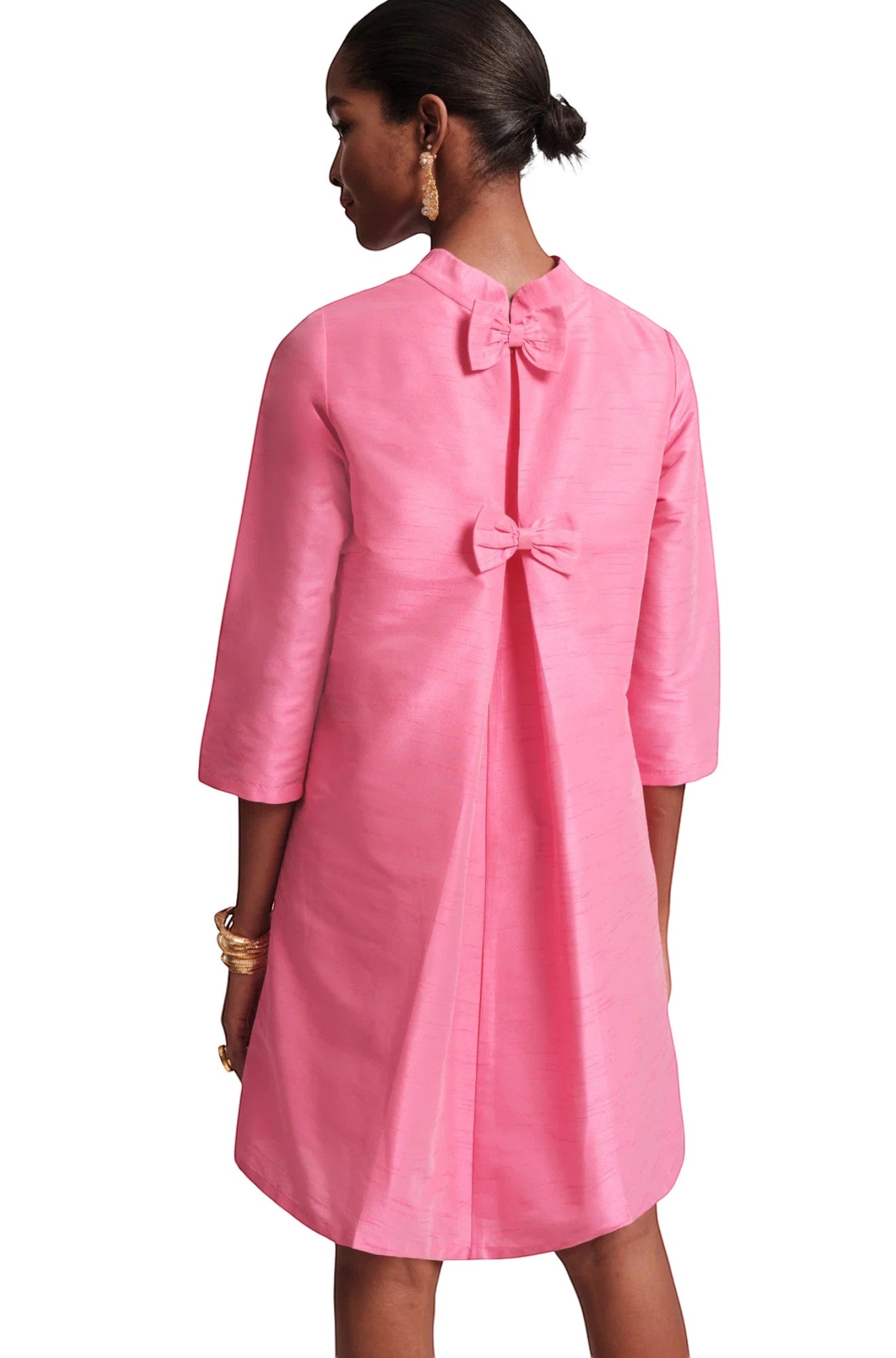 The Copper Shed pink silk mini dress with mock neckline, 3/4 sleeves, and two decorative bows on the back.