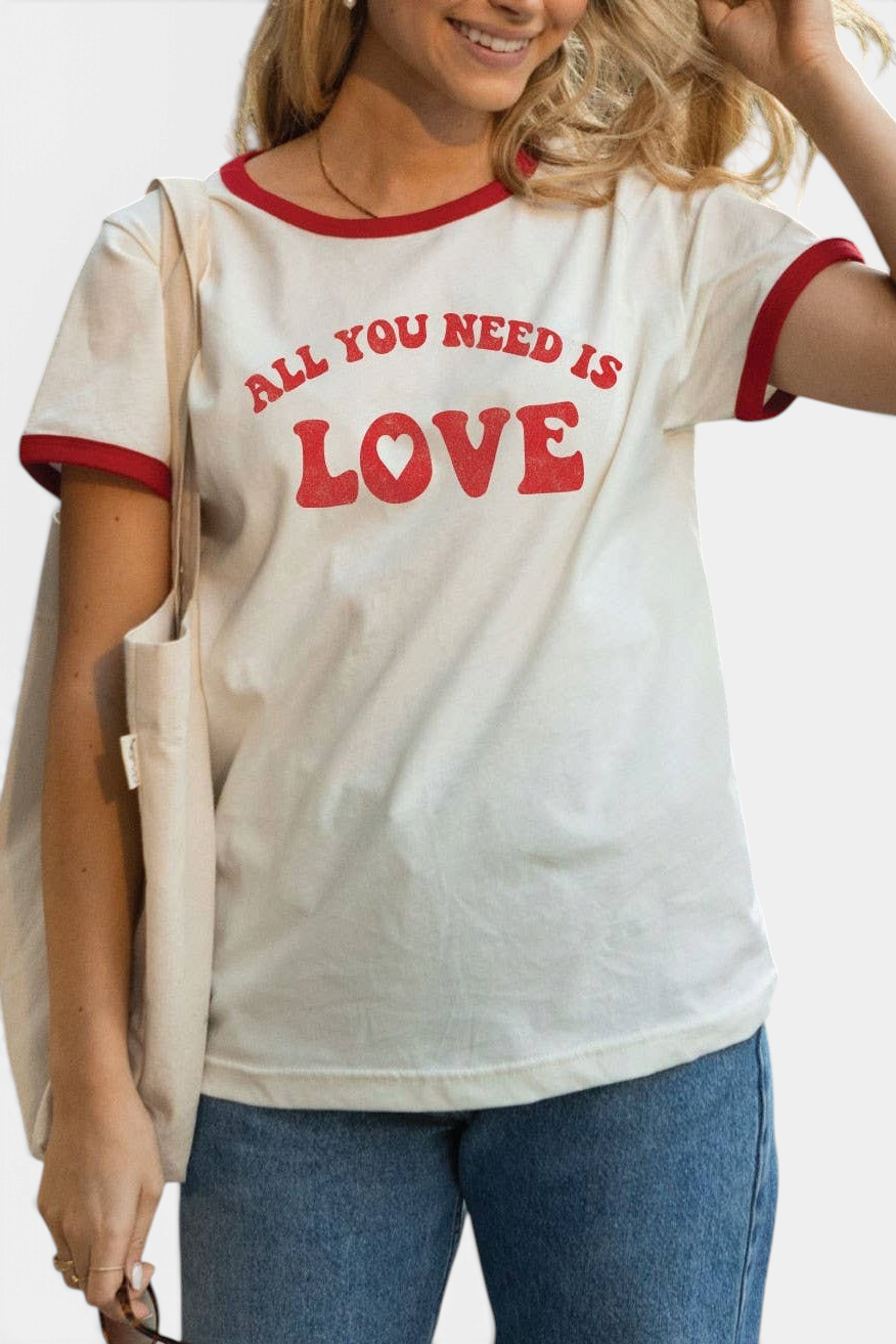 The Copper Shed ringer t-shirt in white cotton with red trim and All You Need Is Love graphic print on a woman.