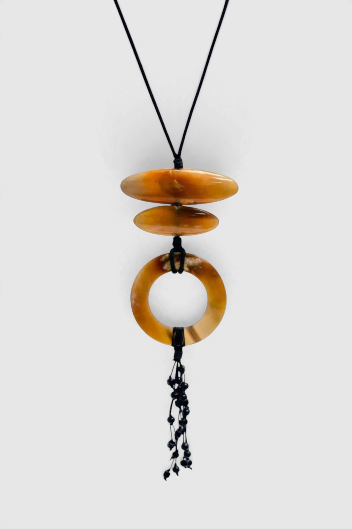 The Copper Shed Sabi Sand beaded necklace featuring amber-toned resin discs and a black waxed cord with bead accents.