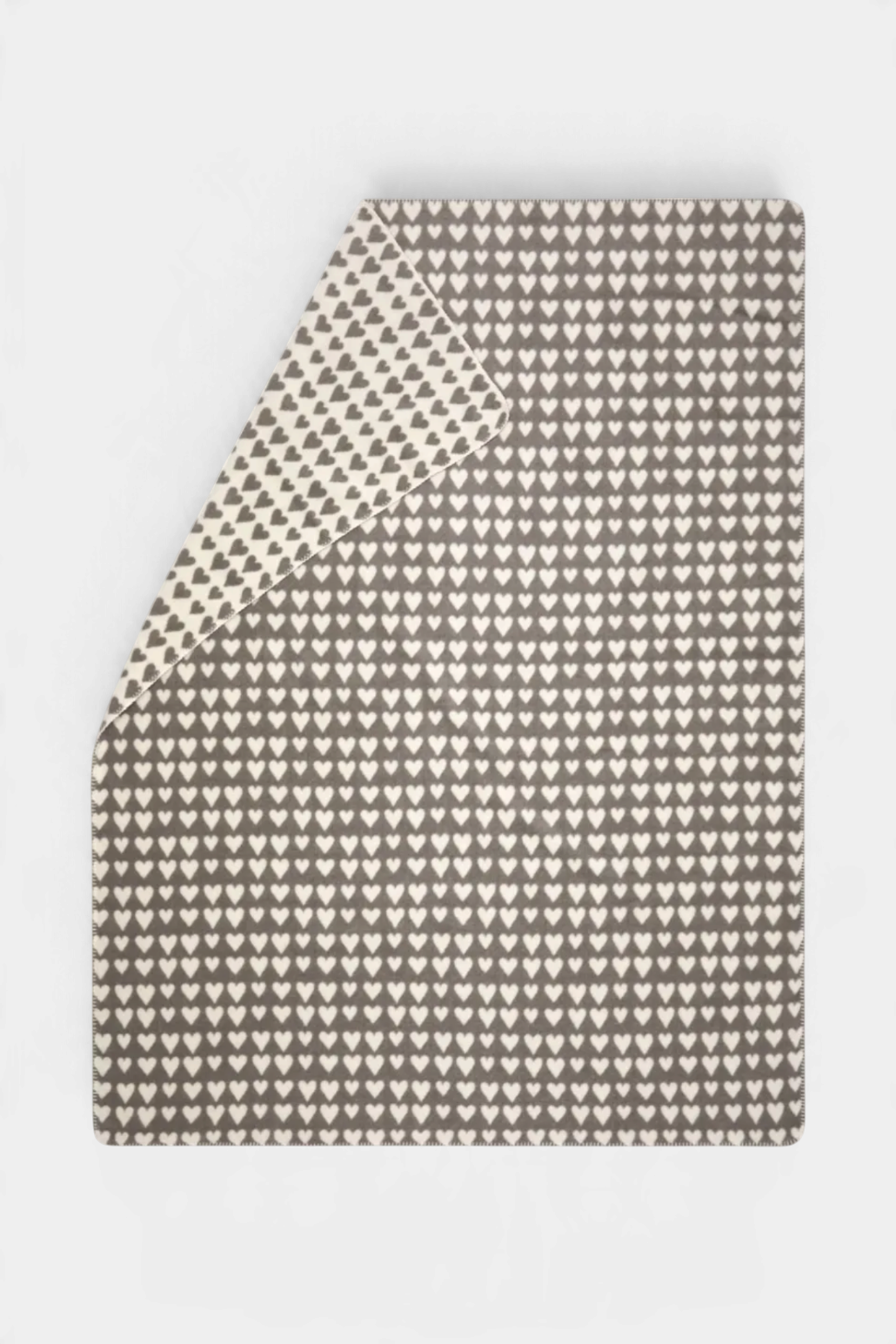 The Copper Shed SAVONA velour throw blanket in grey and cream with a repeating heart pattern and decorative stitch.