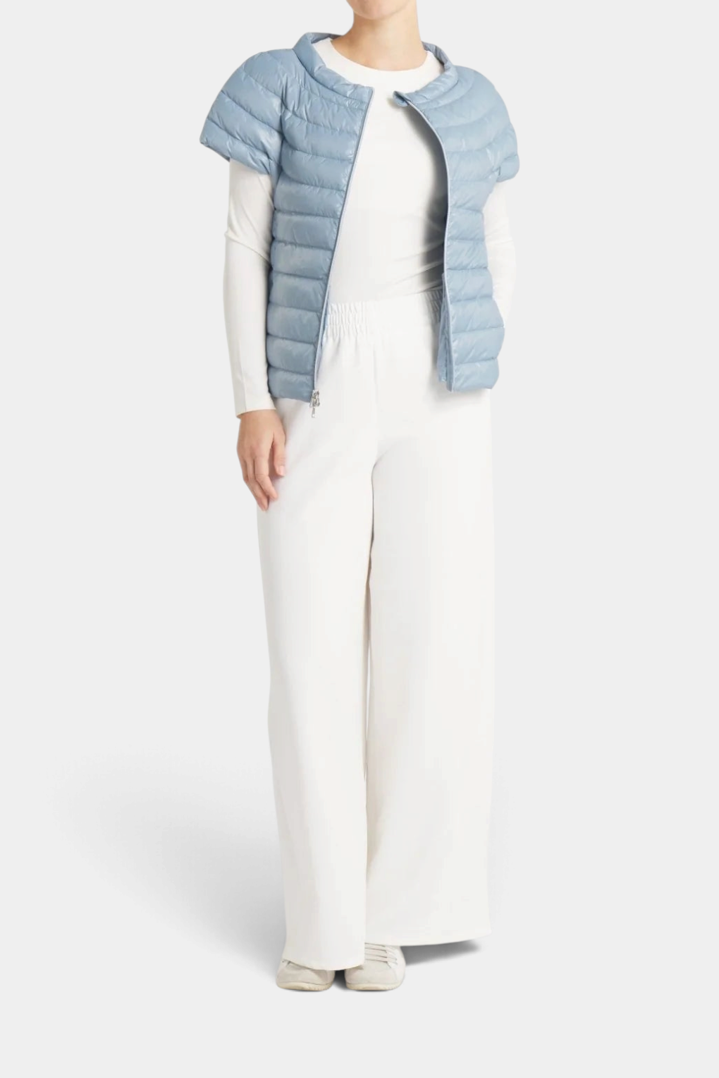 The Copper Shed St Ives light blue packable down vest with quarter sleeves worn over a white long-sleeve top and pants