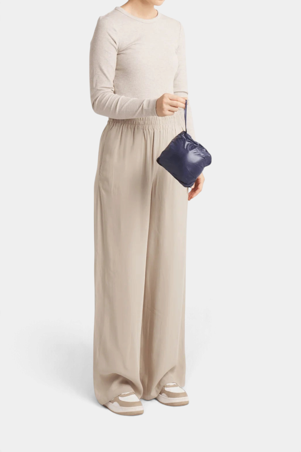 The Copper Shed St Ives down vest packed into its small navy blue storage pouch held by a model in neutral clothing