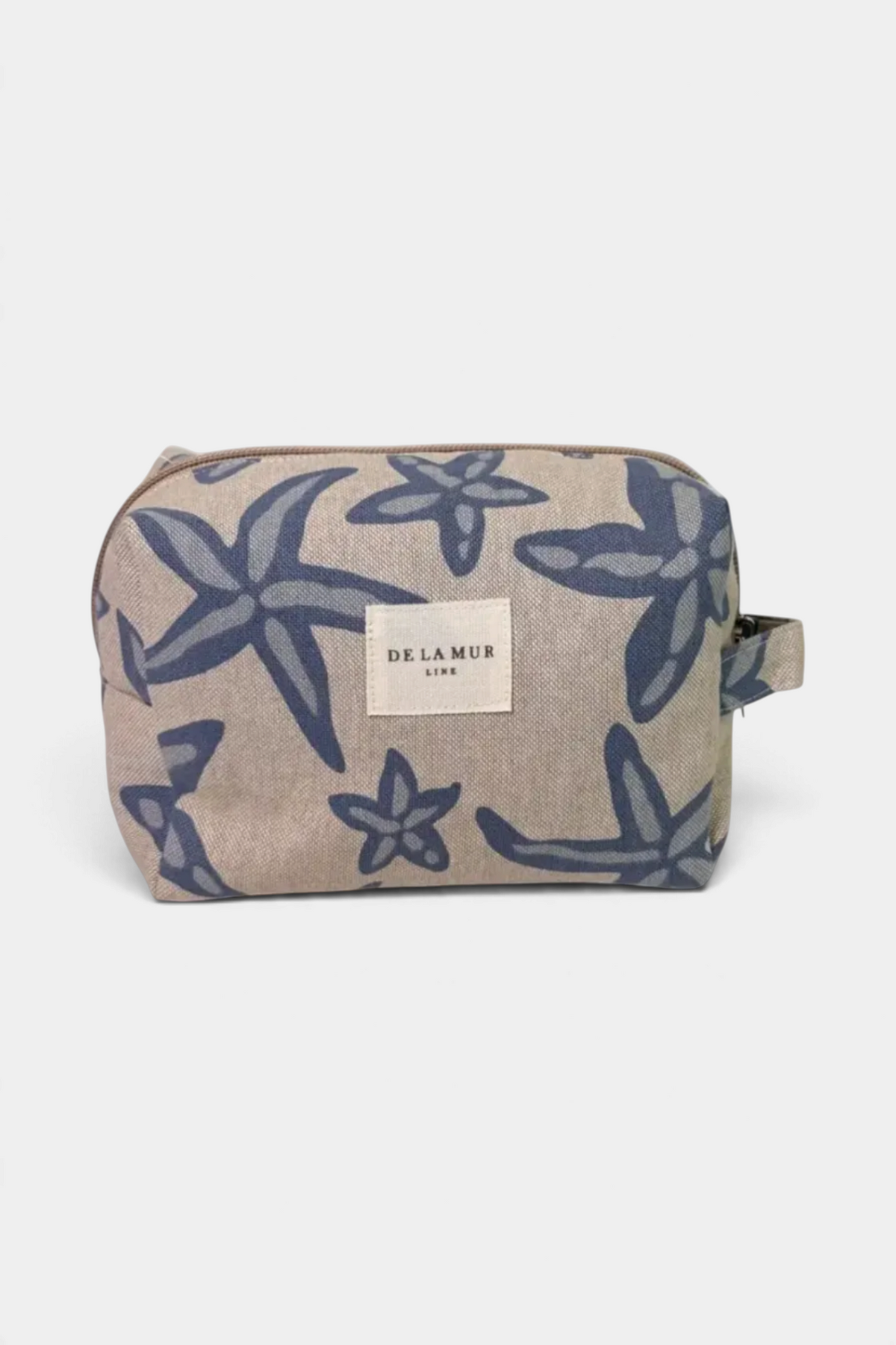The Copper Shed medium makeup bag in beige fabric with a blue starfish print, featuring a side handle and zip closure.