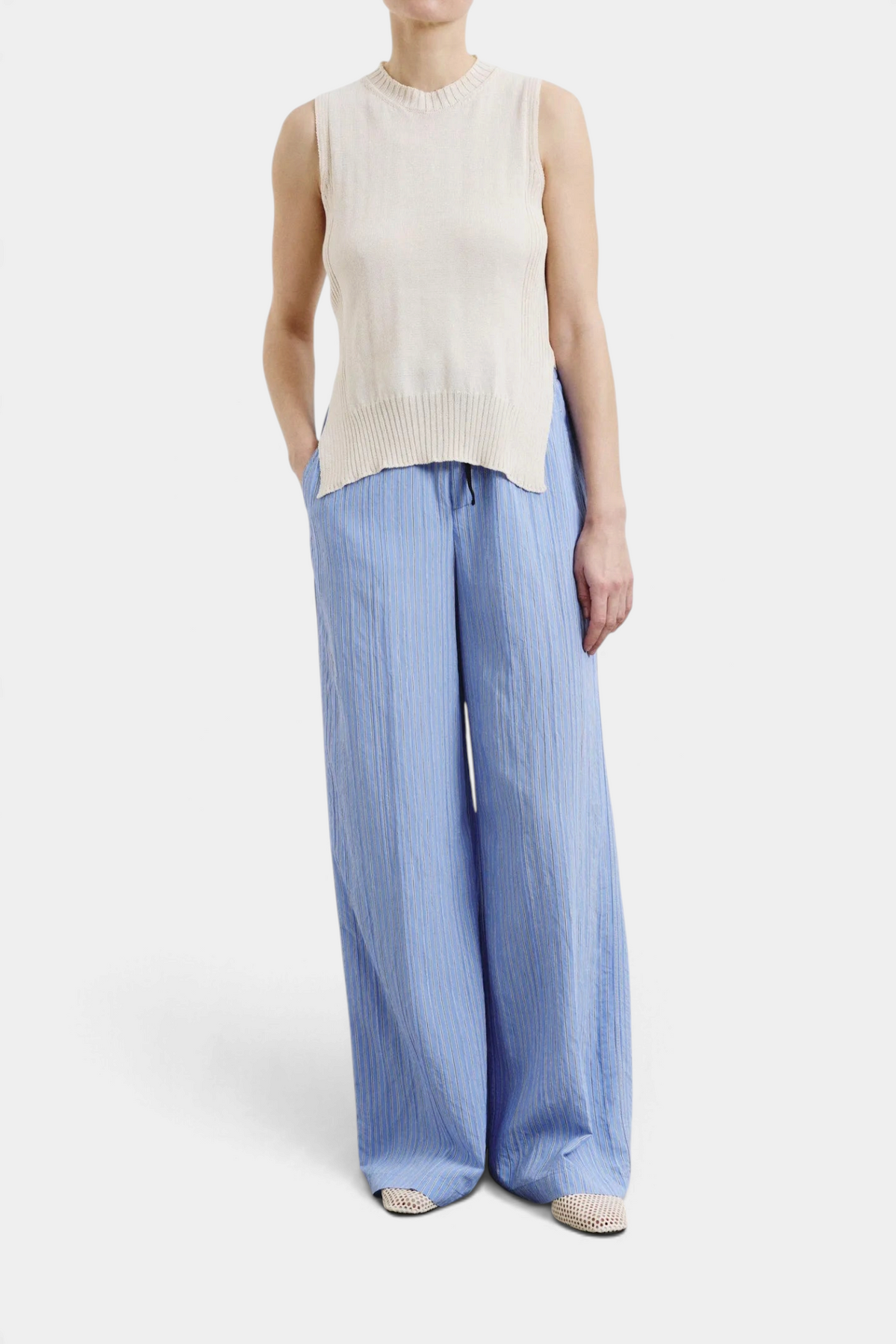 The Copper Shed striped blue technical viscose wide-leg trousers worn with a beige sleeveless knit top