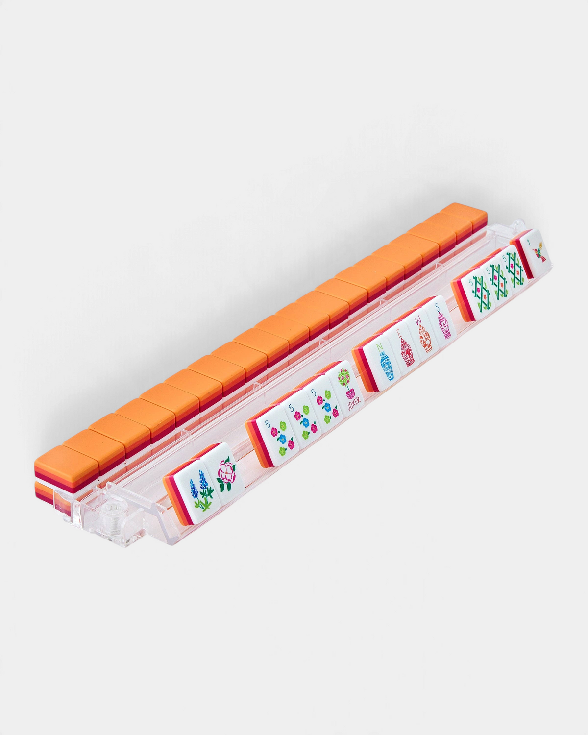 The Copper Shed Sunset Tiles set featuring vibrant coral, orange, and pink acrylic mahjong tiles in a clear rack.