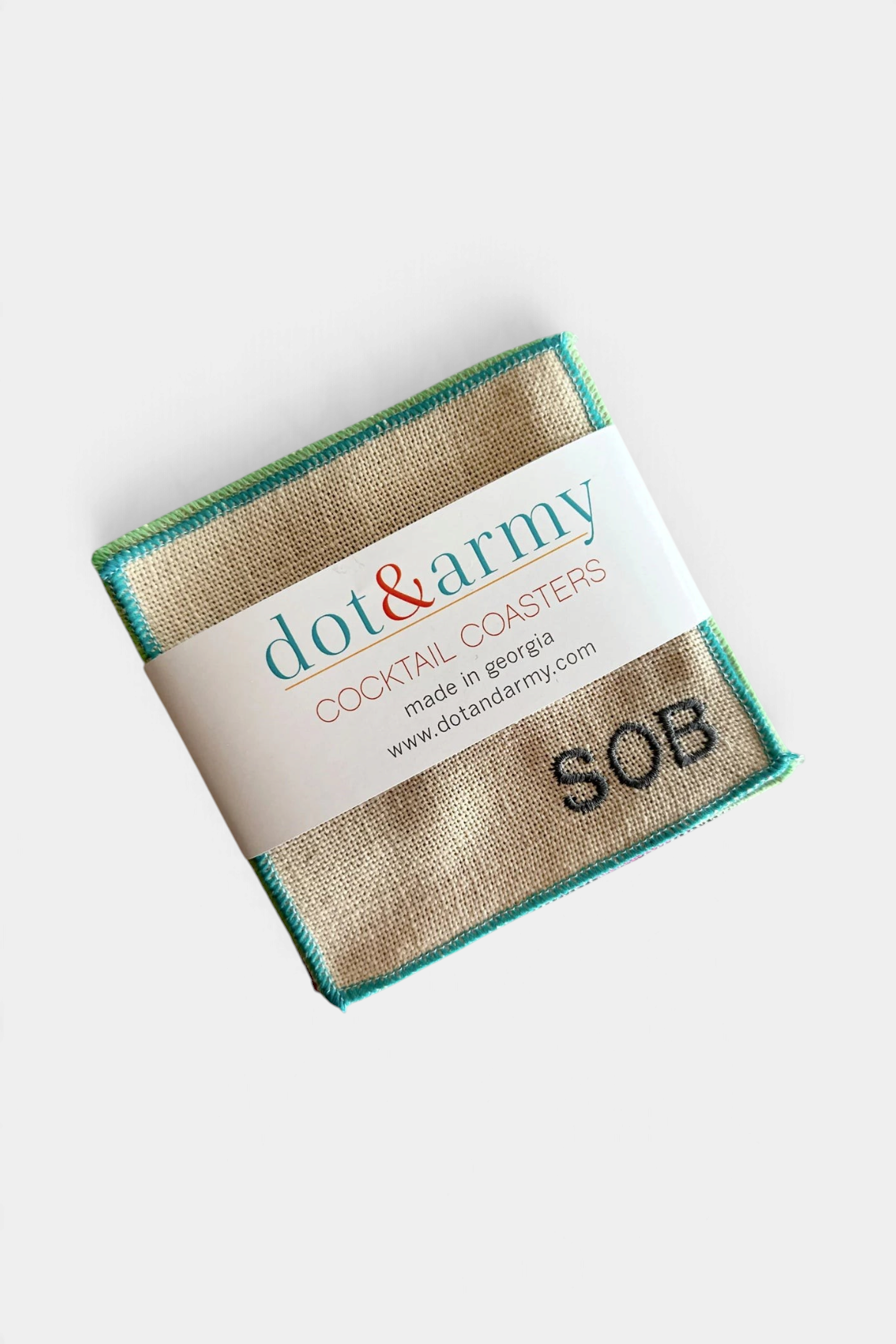 The Copper Shed square linen blend cocktail coaster with embroidered SOB monogram and colorful stitched edges.