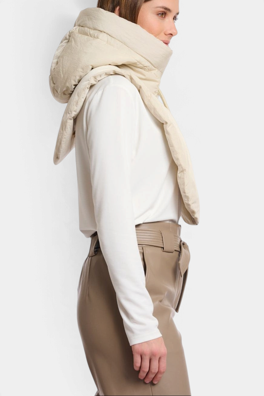 The Copper Shed Rino & Pelle Tabita padded bib in peated beige, worn over a white long-sleeve top, side view.