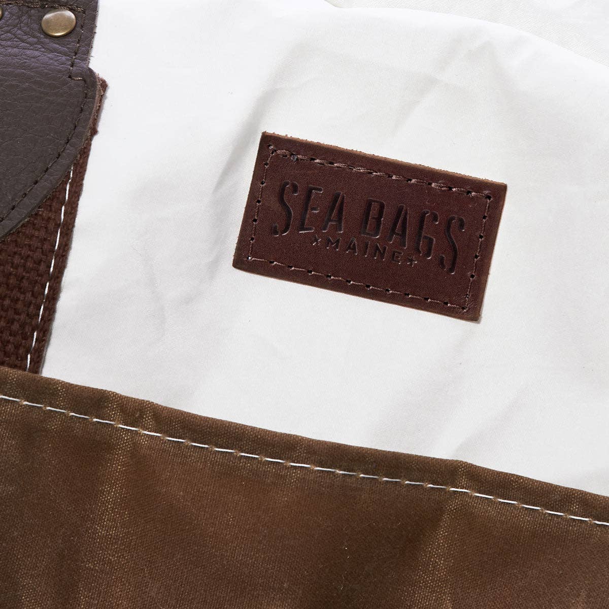 The Copper Shed Tan Chebeague Weekender bag featuring white recycled sail cloth, brown waxed canvas, and leather logo.