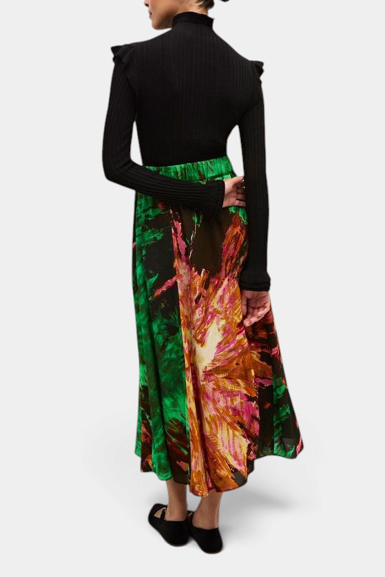 The Copper Shed Tinley black ribbed turtleneck with ruffle trim worn with a vibrant green and pink patterned skirt