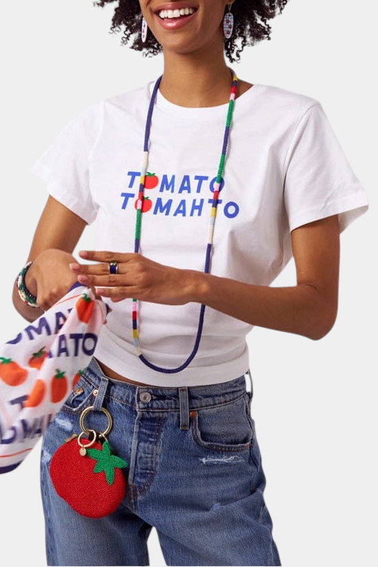 The Copper Shed white graphic t-shirt featuring Tomato Tomahto text and a small red tomato icon on a woman