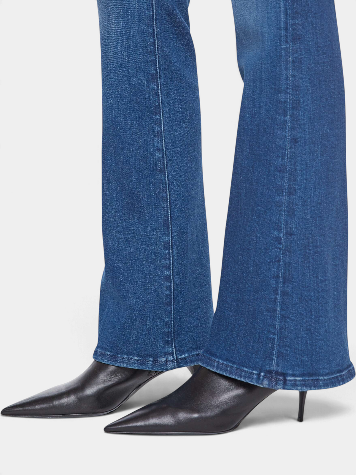 The Copper Shed The Weekender mid-rise flare jeans in medium wash denim with a clean hem, paired with black boots.